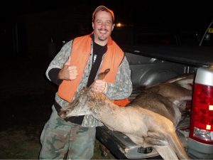 Undercover Maine game warden posing as Bill Freed with a poached deer at night.